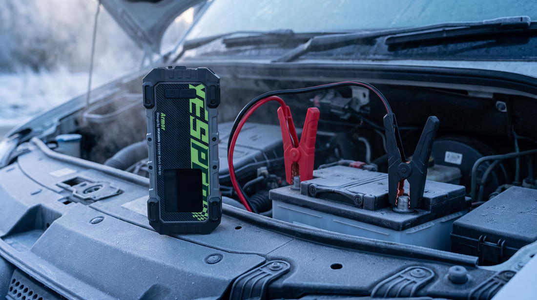 Yesper Armor jumpstarter aangesloten op de accu van een dieselmotor op een koude winterochtend, met de rode klem op de pluspool en de zwarte klem op de minpool