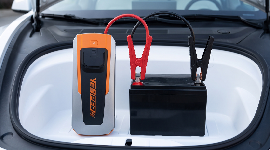 Yesper Fast II jumpstarter aangesloten op de 12V-accu in de voorbagageruimte van een elektrische auto: rode klem op de pluspool, zwarte klem op de minpool